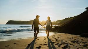 Couple walking on beach holding hands.