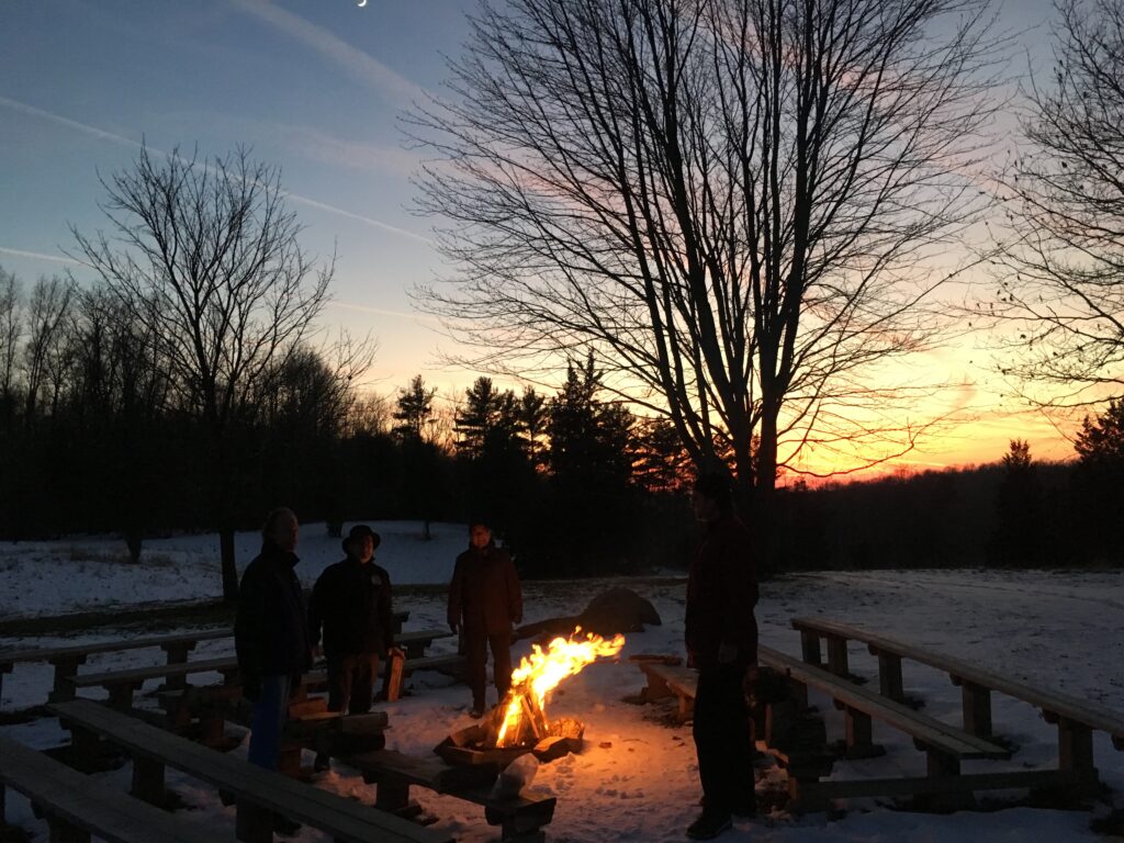Men standing around a bonfire at Sunrise